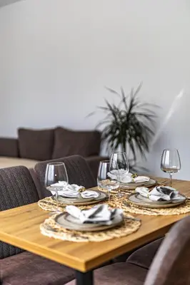 a wooden table with wine glasses and napkins at Saulės Tako apartamentai in Druskininkai
