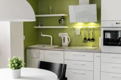 a kitchen with green walls and white cabinets and a table at HaPPy Inn VIP, Self Check-In-24x7, A-C, Parking-in-the-underground-Garage in Vilnius