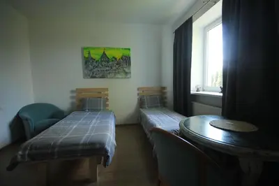 a room with two beds and a table and a window at Svečių namai prie Širvintų in Akmeniai