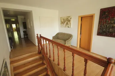 a room with a staircase with a chair and a couch at Svečių namai prie Širvintų in Akmeniai