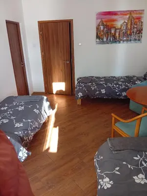 a room with two beds and a wooden floor at Svečių namai prie Širvintų in Akmeniai