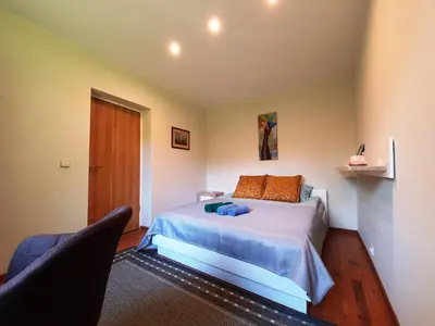 a bedroom with a bed and a chair in it at Apartamentai ŠERMUKŠNIS in Druskininkai