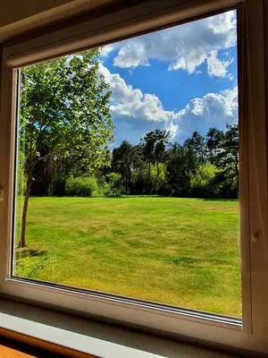 a window with a view of a field of grass at Apartamentai ŠERMUKŠNIS in Druskininkai