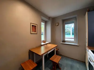 a small kitchen with a desk and two windows at Apartamentai ŠERMUKŠNIS in Druskininkai
