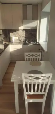 a kitchen with a white table and two chairs at Butas miesto centre/ Apartment in the city center in Šiauliai