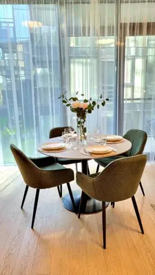 a dining room table with chairs and a vase with flowers at Park Premium Apartments in Birštonas