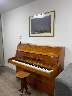 a wooden piano in a room with a stool at APARTMENTS IN THE CITY CENTER BIRŽAI Vytauto g22 in Biržai