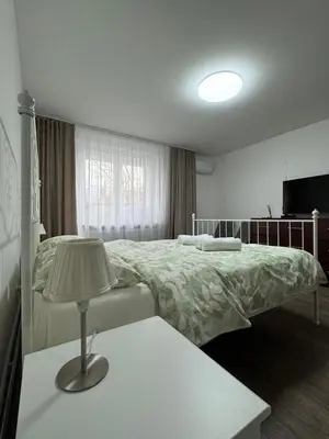a bedroom with a bed and a table with a lamp at APARTMENTS IN THE CITY CENTER BIRŽAI Vytauto g22 in Biržai