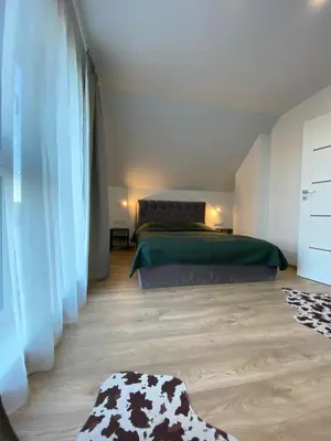 a bedroom with a bed with green sheets and a cow rug at Atostogų namas Twins in Druskininkai