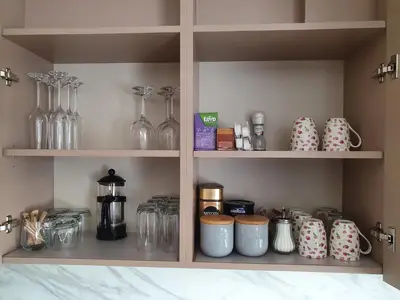 a shelf filled with glasses and other items in a kitchen at 2-bedrooms apartment in city center Šiauliai in Šiauliai