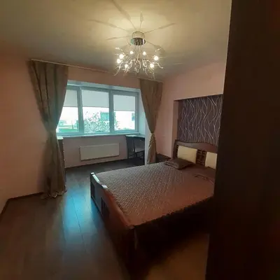 a bedroom with a bed and a chandelier and a window at Jaukus butas Druskininkuose in Druskininkai