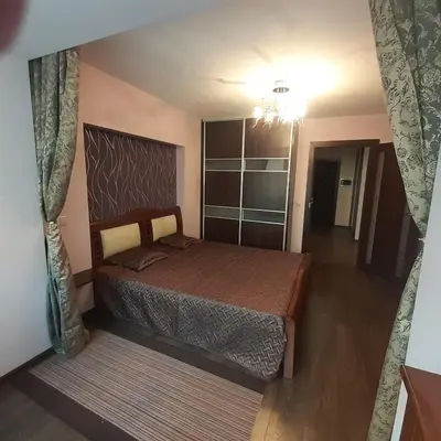 a bedroom with a large bed and a chandelier at Jaukus butas Druskininkuose in Druskininkai