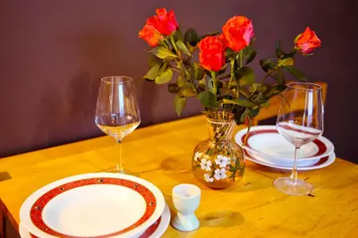 a table with two glasses and a vase with red roses at Apartment for a short rent in KaunasButas trumpalaikei nuomai Kaune in Kaunas