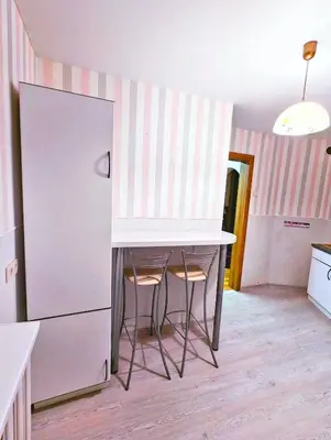 a kitchen with a table and two stools next to a refrigerator at Apartment for a short rent in KaunasButas trumpalaikei nuomai Kaune in Kaunas