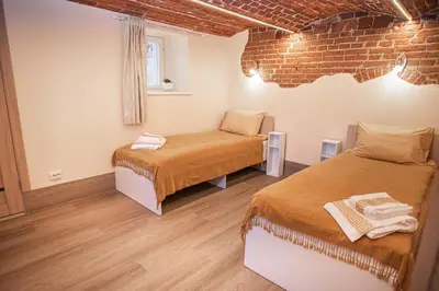 a room with two beds and a brick wall at Lapių Ola in Utena