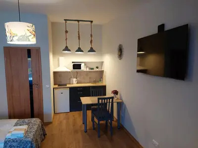 a small room with a kitchen and a table with a chair at Lapių Ola in Utena