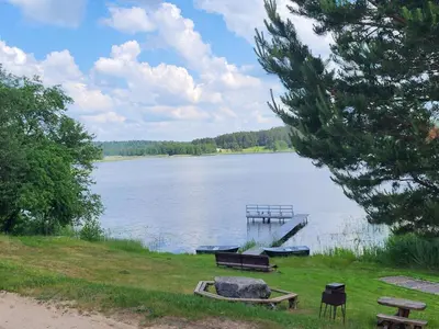 a view of a lake with benches and a dock at Sodyba 