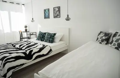 two beds in a white room with a zebra blanket at Šviesos Apartamentai in Anykščiai