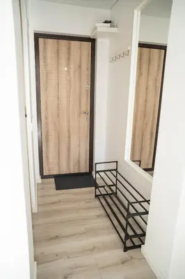 a hallway with a wooden floor and a wooden door at Šviesos Apartamentai in Anykščiai