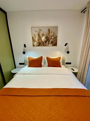 a bedroom with a large bed with orange pillows at Alėjos Apartmentai City in Druskininkai