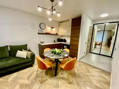 a living room with a table and a green couch at Alėjos Apartmentai City in Druskininkai