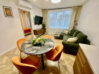 a living room with a glass table and chairs at Alėjos Apartmentai City in Druskininkai