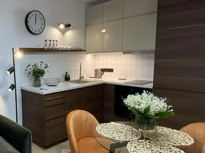 a kitchen with a table and a clock on the wall at Alėjos Apartmentai City in Druskininkai