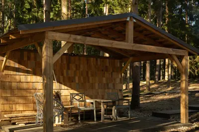 a wooden pavilion with a table and chairs at Private cosy forest cabin in Inturkė