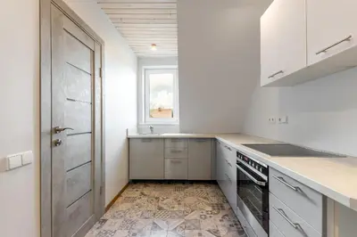 a kitchen with white cabinets and a sink and a door at Shanghai Banzai Family Apartment Vilnius in Vilnius