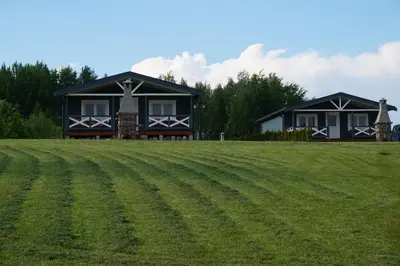 a house in the middle of a grass field at R&M Resort in Petkėniškės