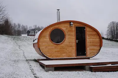 a wooden hobbit house with a door on a road at R&M Resort in Petkėniškės