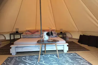 a bed in a tent with a table at Natur Camp Glamping Birštonas in Birštonas