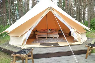 a tent with a table and chairs on a deck at Natur Camp Glamping Birštonas in Birštonas