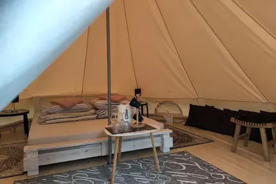 a bed in a tent with a table at Natur Camp Glamping Birštonas in Birštonas