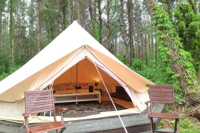 a canvas tent with two chairs and a bed at Natur Camp Glamping Birštonas in Birštonas