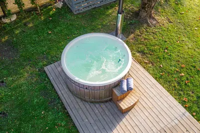 a large bath tub sitting on a wooden deck at Namelis ant ežero kranto 