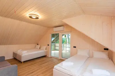 a attic room with two beds and a window at Namelis ant ežero kranto 