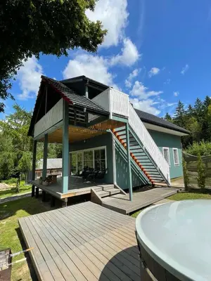 a house with a deck and stairs on it at Namelis ant ežero kranto 