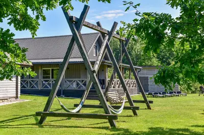 a swing set in front of a house at Sodyba Pivašiūnuose ant ežero kranto in Pivašiūnai