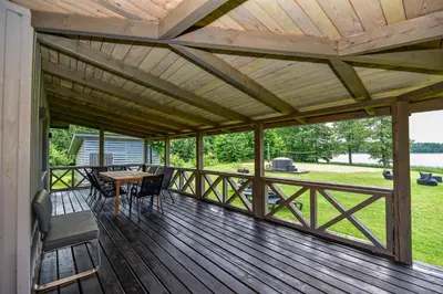 a large wooden deck with a table and chairs on it at Sodyba Pivašiūnuose ant ežero kranto in Pivašiūnai