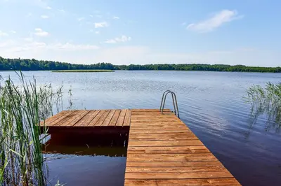 a wooden dock on a large body of water at Sodyba Pivašiūnuose ant ežero kranto in Pivašiūnai