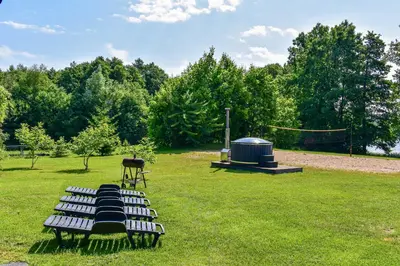 a group of benches sitting in a park with a volleyball court at Sodyba Pivašiūnuose ant ežero kranto in Pivašiūnai