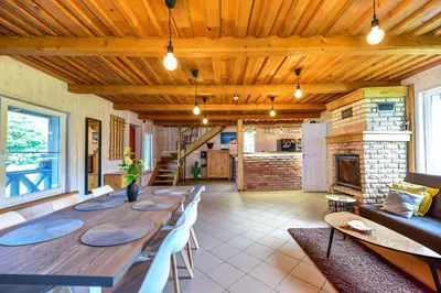 a dining room with a long table and a fireplace at Sodyba Pivašiūnuose ant ežero kranto in Pivašiūnai
