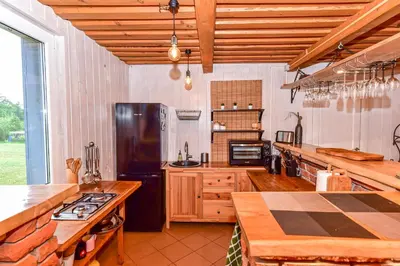 a large kitchen with a black refrigerator and wooden counters at Sodyba Pivašiūnuose ant ežero kranto in Pivašiūnai
