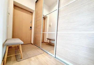 a glass shower door in a room with a stool at MELODIJA apartments in Druskininkai center in Druskininkai