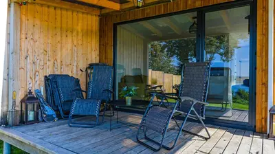 a porch with four chairs and a table on it at Volunge house in Doškonys