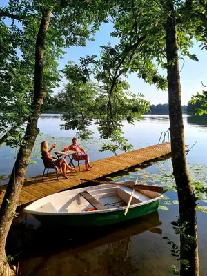 two people sitting at a table on a dock with a boat at Volunge house in Doškonys