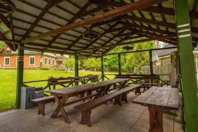 a group of picnic tables under a wooden pavilion at Alaušo Salos - Malinauskų kaimo turizmo sodyba in Sudeikiai