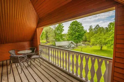 a balcony with a table and chairs and a large window at Alaušo Salos - Malinauskų kaimo turizmo sodyba in Sudeikiai
