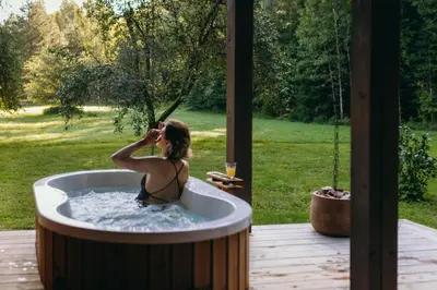 a woman in a jacuzzi tub in a yard at ALNUS KIEMAS in Kampiškiai
